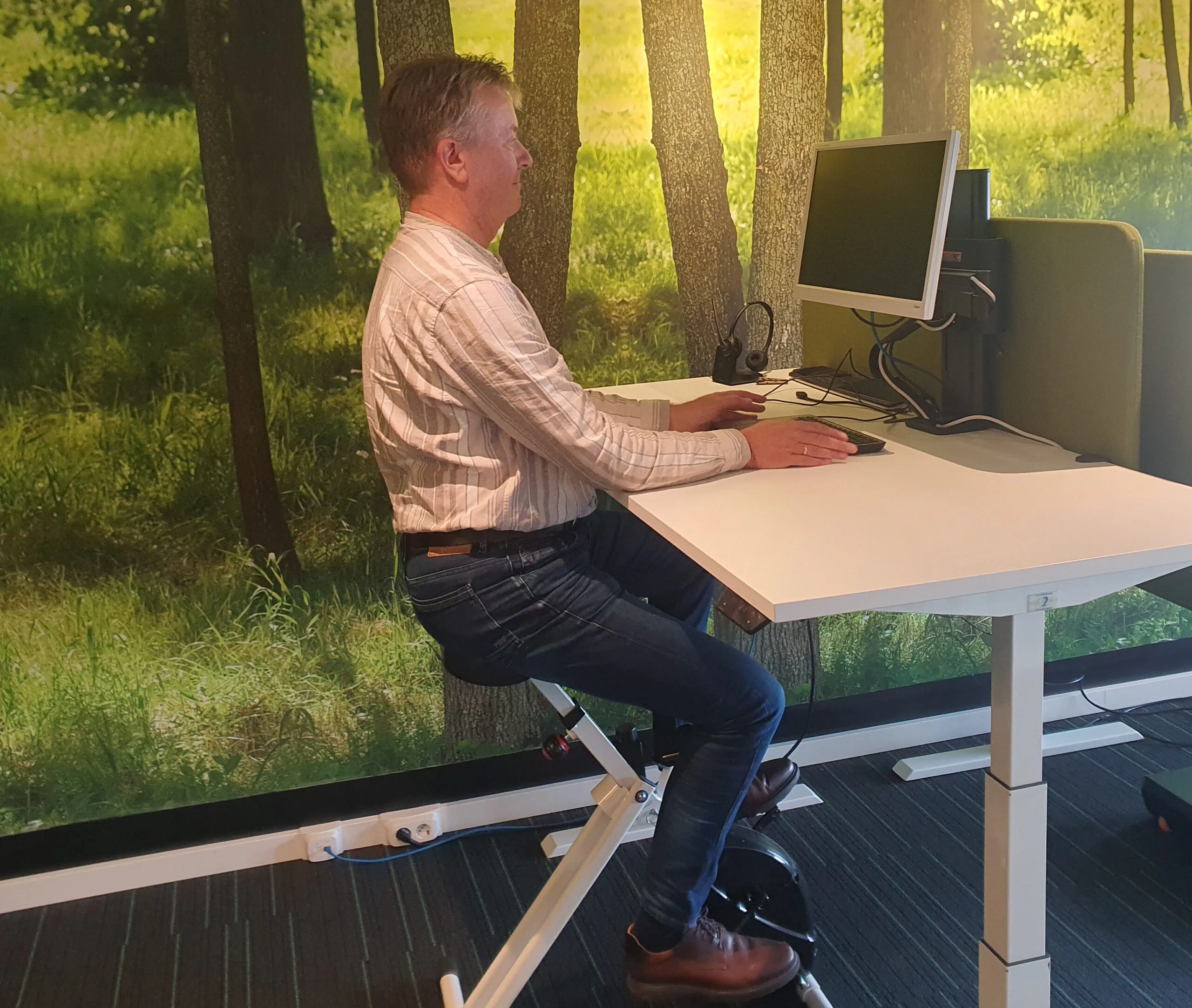 Roy Versteegen op een bureaufiets tijdens een werkbezoek bij Health2work in Blaricum